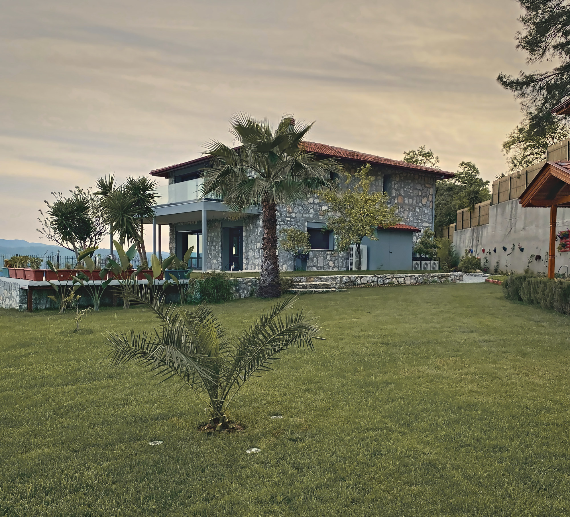 The stone main house across the lawn, palms in the garden and the hills beyond